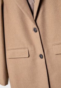 Mantel aus Kamelwollmischung mit Reverskragen, zwei vorderen Taschen und schwarzen Knöpfen, der eine glatte Textur und ein strukturiertes Design aufweist.