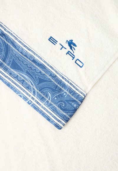 Serviette blanche avec une bordure bleue à motif cachemire et un logo brodé bleu représentant un cheval et le nom de la marque "ETRO" près du bord.
