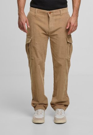 Beige Corduroy Cargo-Hosen mit zwei Seitentaschen, Knopfverschluss vorne und strukturiertem Stoff. Kombiniert mit weißen Sportschuhen.