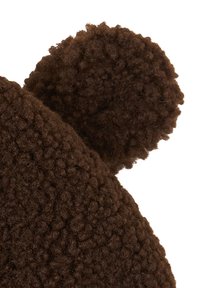 Bruine gebreide muts met een fuzzy, gestructureerde stof en twee ronde oorachtige accenten bovenop. Het materiaal lijkt zacht en comfortabel te zijn.