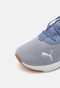 Sneaker azzurro chiaro con parte superiore in rete testurizzata, suola in gomma e colletto imbottito. Presenta un marchio bianco sul lato e una copertura in gomma caramello sulla punta.