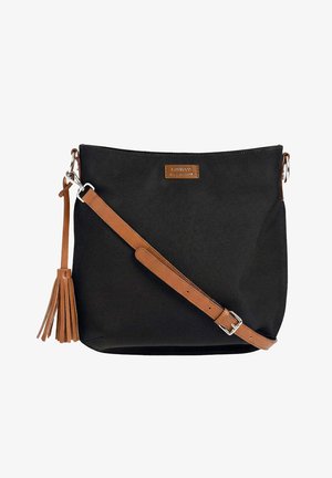 Sac bandoulière en tissu noir avec une sangle en cuir marron ajustable et un pompon, doté d'un petit patch logo marron.