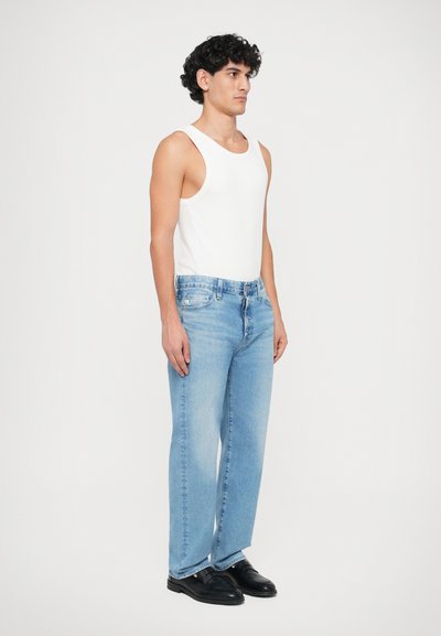 Heledad hall denim teksad, mis on sirge lõikega, koos tiheda valge tanktopi ja mustade kleitkingadega. Lihtne ja puhas disain.