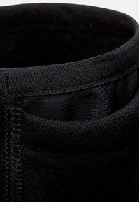 Black fabric tube with a smooth inner lining. Textured exterior with visible stitching, featuring a rounded top edge without any patterns.