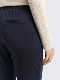 Pantalones navy con cinturilla elástica, que cuentan con un único bolsillo trasero. La tela tiene una textura suave, combinada con una camiseta de manga larga con finas rayas.