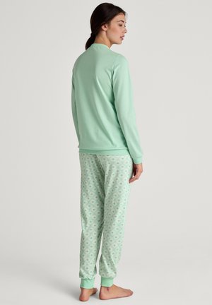Completo pigiama verde menta con una maglietta a manica lunga in tinta unita e pantaloni con polsini elasticizzati decorati con motivi floreali e geometrici.