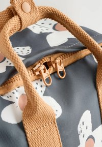 Purple backpack with a floral pattern, featuring zippers and beige woven handles. Made of durable fabric with a textured finish.