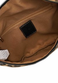 Interno in nylon marrone di una borsa, con una tasca con zip e un'etichetta nera con dettagli di cucitura. Il tessuto è liscio e resistente.