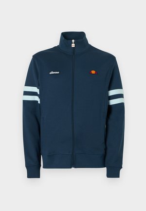 Laivastonsininen vetoketjullinen takki korkealla kauluksella, valkoiset raidat hihoissa ja kirjailtu logo. Pehmeä kangas, joustavat hihansuut ja helma.