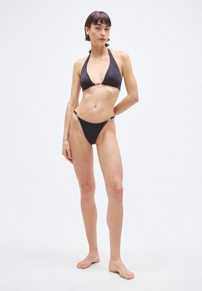 Čierna bikini súprava s topom na viazanie za krk a trojuholníkovými nohavičkami, ozdobená zlatými kovovými detailmi na bokoch. Hladká textúra.