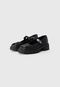 Scarpe Mary Jane nere in pelle con punta tonda, suola spessa e piattaforma, e una sola cinghia con un accento di fibbia in argento.