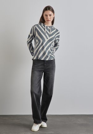 Felpa a righe grigie e crema con cappuccio e cordino, abbinata a jeans scuri larghi e sneakers bianche. Design semplice con vestibilità casual.