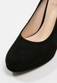 Black suede high heel shoe with a rounded toe and a smooth inner lining. Features a slight platform for added height.