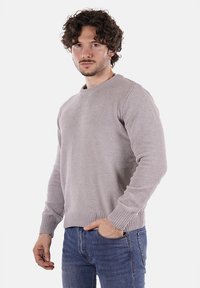 Maglione grigio chiaro con motivo di lavorazione a maglia texture, collo a giro, e polsini e orlo a coste, indossato con jeans in denim blu.