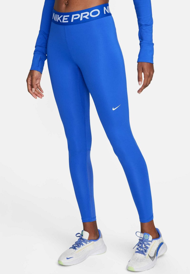 Leggings Nike Pro azules con una cinturilla de logo blanca, que presentan una textura suave y ajustada y un diseño de longitud completa. Llevados con zapatillas ligeras.
