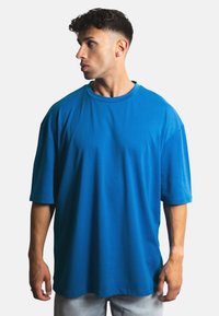 Överdimensionerad t-shirt med kort ärm i klart blått bomull, med rundad halsringning och en avslappnad passform. Slät textur, minimala sömmar.