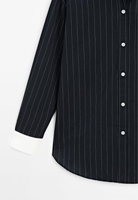 Navy striped shirt featuring a long sleeve, white cuffs, button closure, and a smooth fabric texture with thin vertical lines.