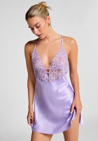 Lavendelkleurige satijnen slipdress met kantdetails; voorzien van verstelbare schouderbandjes, een diepe V-halslijn en een zachte textuur; knielange snit.