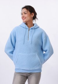 Felpa azzurra morbida con mezzo zip, cappuccio regolabile con coulisse e tasca frontale a marsupio. Presenta polsini e orlo a costine per una maggiore texture.