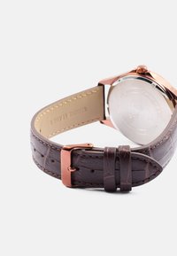 Pulseira de relógio em couro genuíno castanho com textura impressa e hardware em rosa dourado. Apresenta uma caixa metálica redonda com parte traseira lisa.