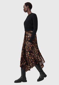 Musta lyhytneule yhdistettynä oranssin- ja ruskeansävyiseen eläinkuosiseen laskostettuun hameeseen sekä mustiin polven yli ulottuviin saappaisiin. Suorat pinnat.