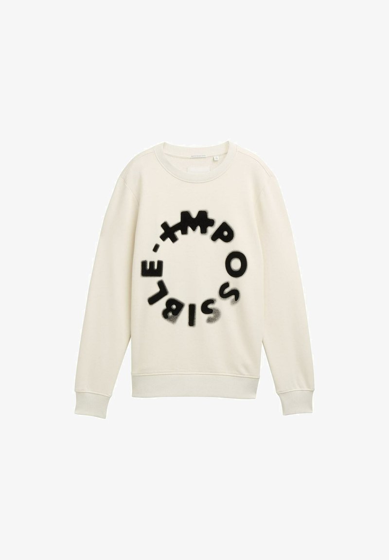 Sweatshirt en tissu doux couleur crème, avec un motif circulaire comportant des lettres noires qui épellent "IMPOSSIBLE" dans des polices et tailles variées.
