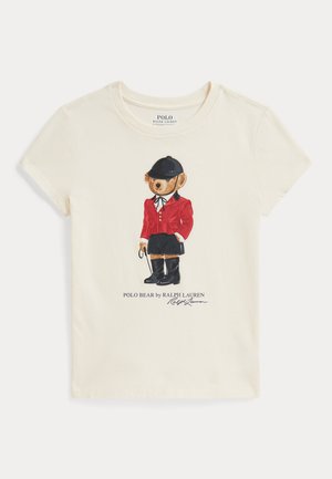 Kremowy t-shirt z misiem w czarnym jeździeckim kasku, czerwonej kurtce, czarnych butach i trzymającym bat, napis Polo Bear autorstwa Ralph Lauren poniżej.