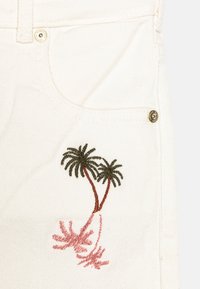 Biała tkanina dżinsowa z przednią kieszenią z złotymi akcentami. Wyhaftowany wzór dwóch zielonych palm z różowymi akcentami.