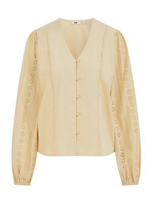 V formos kaklo, smėlio spalvos palaidinė su ilgomis rankovėmis, sagų užsegimu ir akių raštais ant rankovių ir priekyje. Pagaminta iš lengvo audinio.