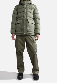 Olivegrüner Pufferjacke mit Reißverschluss und Druckknopfverschluss, großen Vordertaschen und Kapuze; kombiniert mit passenden olivfarbenen Cargo-Hosen.