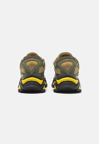 Sneaker verdi e neri con dettagli gialli, pannelli in rete, colli imbottiti, suole robuste e un design posteriore distintivo con dettagli del logo.