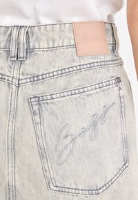 Lichtgewicht denim jeans hebben een leren patch op de tailleband met een geperst logo. De stiksels zijn zichtbaar langs de naden en zakken.