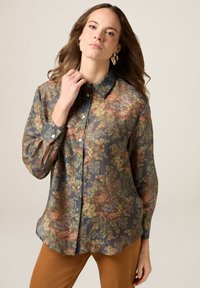 Kwiatowa koszula na guziki z przezroczystego materiału, w odcieniach granatu, pomarańczy i zieleni, z klasycznym kołnierzykiem i długimi rękawami.