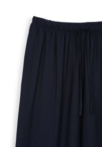 Tessuto leggero di un blu navy scuro con vita elastica e cordoncino. Texture morbida, forma non strutturata, adatta per un abbigliamento casual.