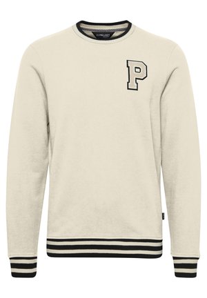 Tejfehér pulcsi fekete bordázott mandzsettákkal és aljjal, amelynek mellkasán egy kiemelkedő fekete-fehér "P" betű hímzése található.