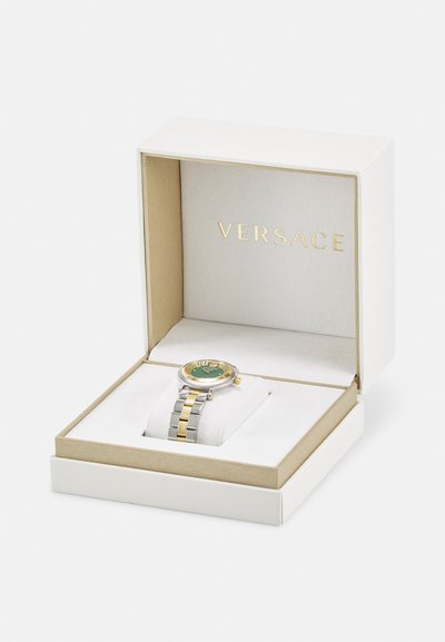 Gold and silver Versace watch in a white box, featuring a green face, patterned bezel, and a stainless steel and gold bracelet.