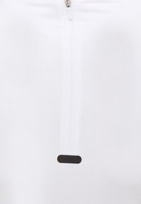 Weißes Zip-up-Oberteil mit einem verdeckten Reißverschluss und einem kleinen schwarzen Akzent am Saum. Glatter Stoff mit einem klaren, minimalistischen Design.