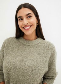 Maglione lavorato a maglia di un verde oliva con superficie testurizzata, scollatura rotonda e maniche arrotolate, realizzato in un morbido mix di tessuti.
