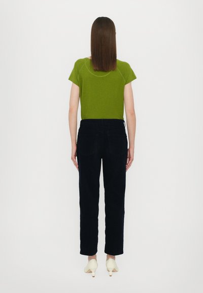 Green short-sleeve shirt, black pants, and cream block-heel shoes. Simple design, cotton material, relaxed fit with minimal detailing.