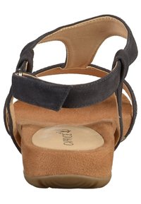 Svarta mockasandaler med flera remmar, öppen häl och en strukturerad tan-färgad fotbotten. Mjuk innervadd och gummisula.