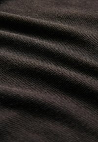 Tessuto scuro con texture a costine diagonali, che mostra una superficie liscia e una leggera lucentezza, riflettendo la luce in tonalità variate.