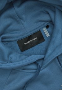 Felpa blu con un morbido rivestimento interno, dotata di cappuccio con coulisse, polsini a coste e un'etichetta con la scritta "PeakPerformance" e taglia M.