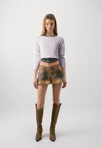 Pulover croșetat lavandă cu mâneci lungi, asociat cu o fustă mini din denim maro cu tiv desfăcut și zone întunecate, și cizme maro până la genunchi.