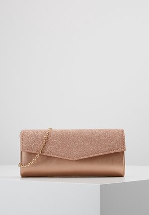 Pochette rectangulaire en or rose avec rabat pailleté et bandoulière chaîne dorée, présentée sur un socle blanc sur fond uni.
