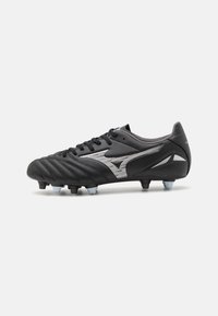 Scarpe da calcio nere con tomaia in pelle testurizzata, chiusura con lacci e dettagli argentati. Presentano tacchetti moldati per una migliore trazione su superfici erbose.