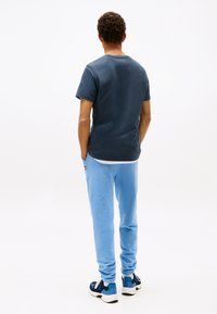 Marinblå t-shirt med korta ärmar, ljusblå mjukisbyxor och svart/blå sneakers. Tyget verkar mjukt med en avslappnad passform och elastiska muddar.