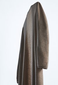 Pullover lungo marrone realizzato in tessuto morbido, con un design dal taglio ampio e colletto rotondo. Le maniche sono leggermente aderenti ai polsi.