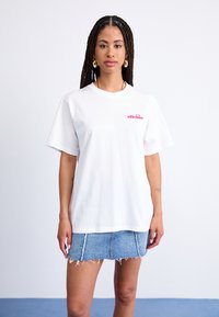 White cotton t-shirt with short sleeves, featuring a pink logo on the left side, paired with a light blue denim mini skirt with frayed edges.