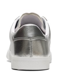 Zapatilla sintética plateada con un tacón metálico texturizado, suela de goma blanca y cuello acolchado para mayor comodidad.