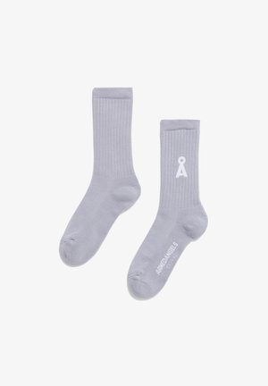 Calze grigio chiaro realizzate in tessuto a costine. Presentano un logo e un testo bianchi sul lato. Forma standard della calza con una struttura morbida e aderente.